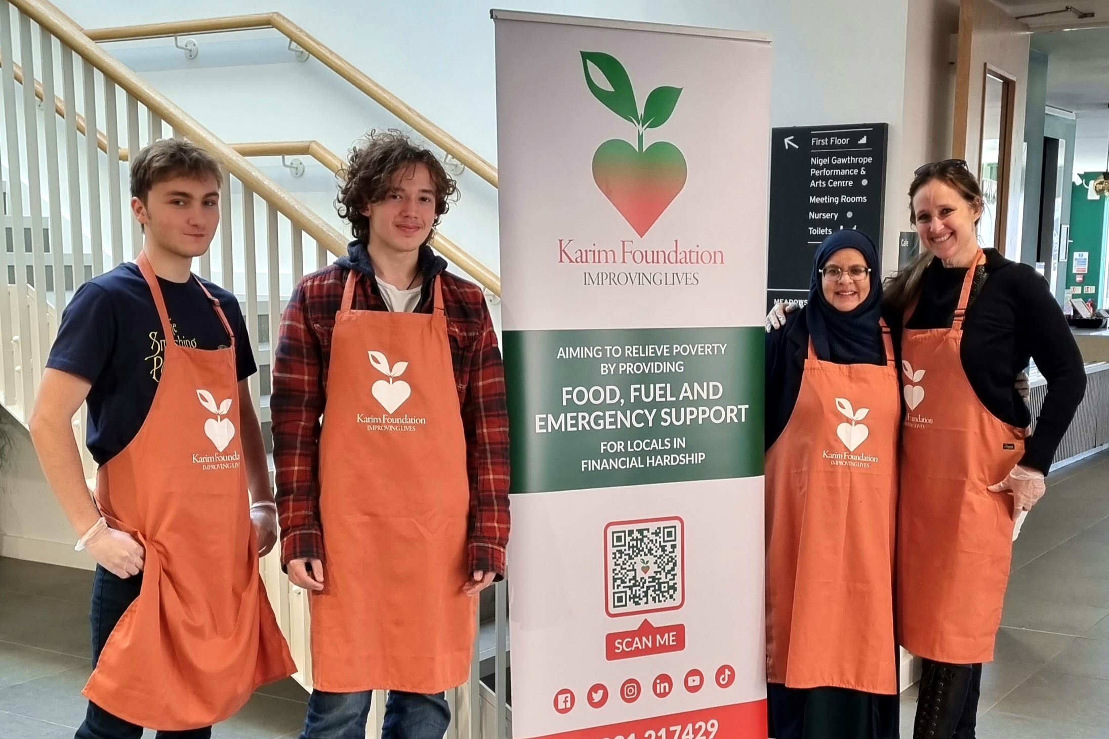 Charles (left), Matthew (second from left), Shahida (second from right) and Jeandre (right) open the doors to the North Cambridge Soup Kitchen. They are all wearing orange Karim Foundation aprons
