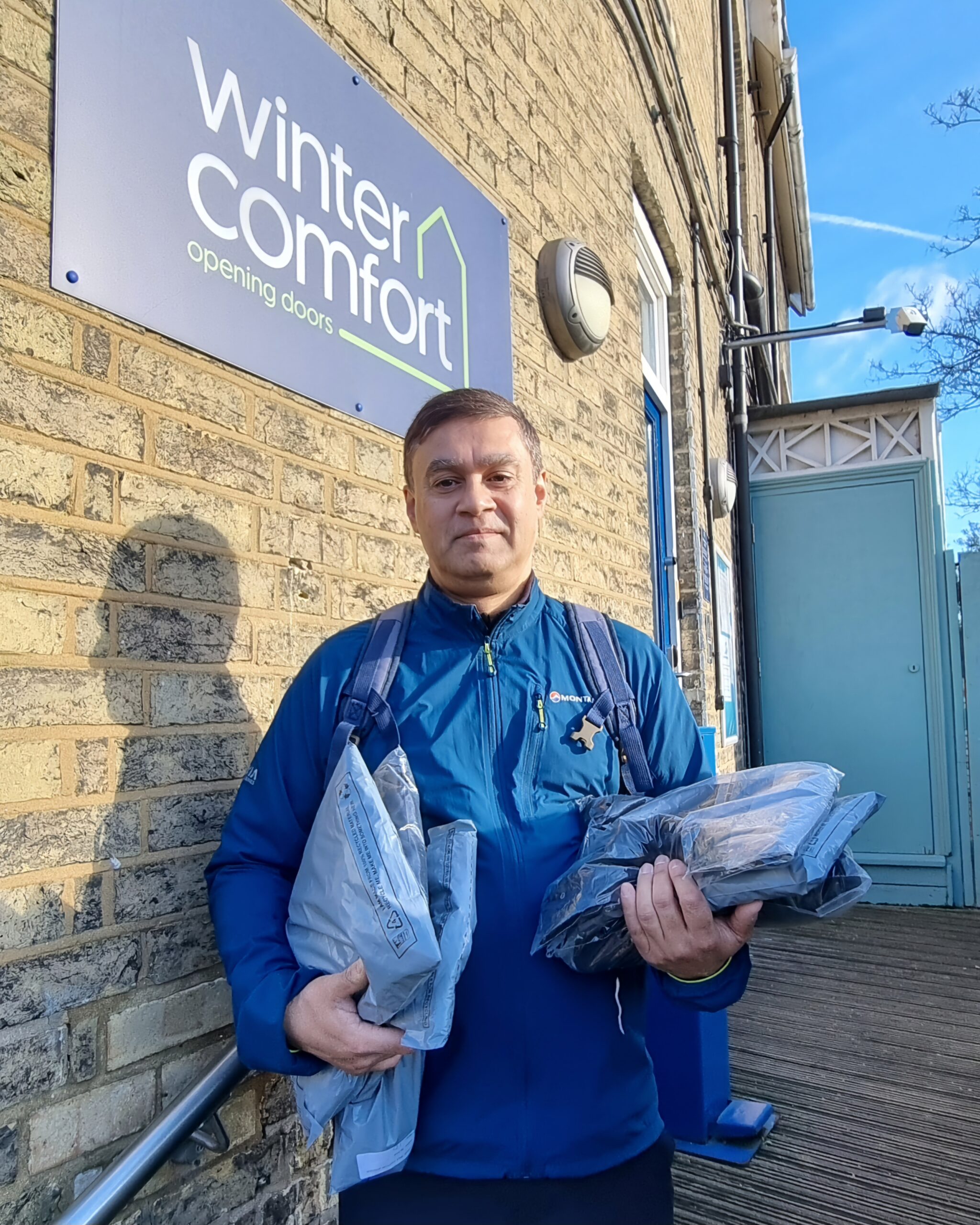 Kal Karim stands outside Wintercomfort carrying some fleeces and joggers to support women facing homelessness