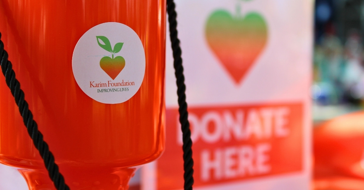 The Karim Foundation collection pot in the foreground and a sign that reads "Donate Here" in the background.